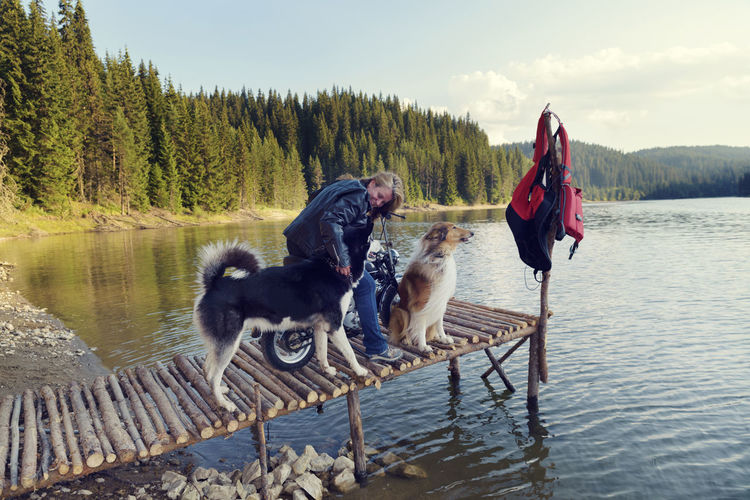 Woman standing with dogs by lake on pier