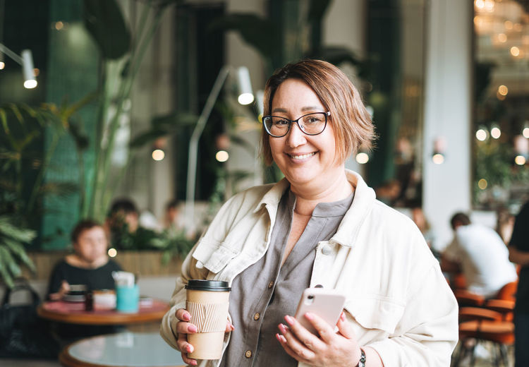 Adult brunette middle aged woman plus size body positive in casual clothes with coffee in cafe