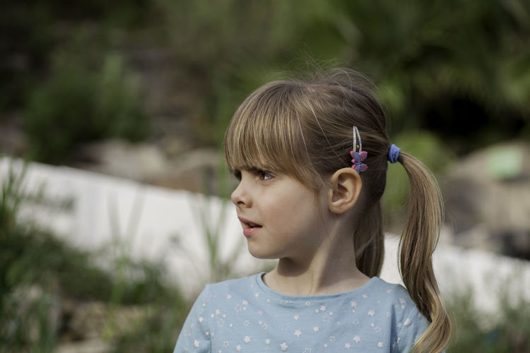 Close-up of confused girl looking away while standing in yard