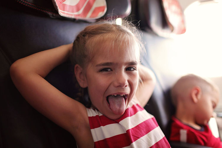 Girl sticking out tongue while sitting on seat