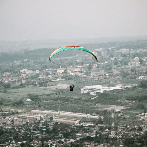 People paragliding over cityscape against sky