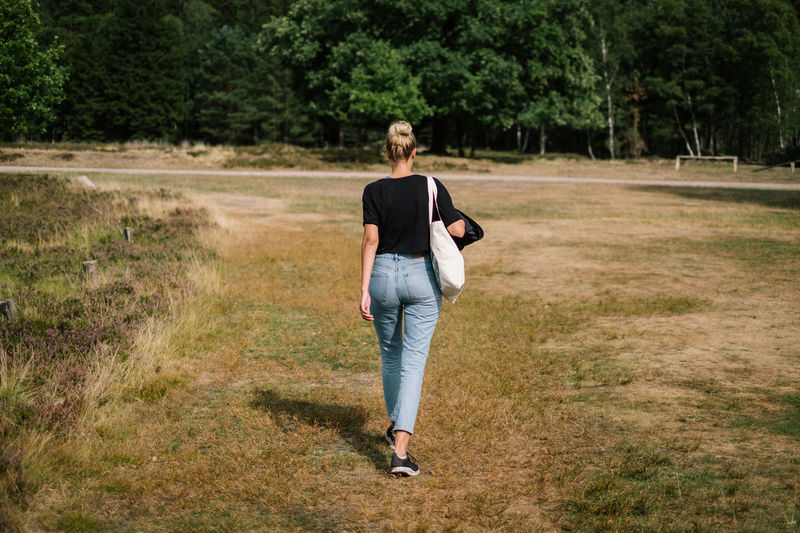Rear view of woman walking on field