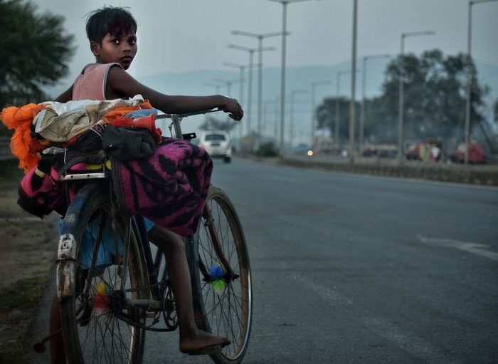 Boy riding bicycle on road in city
