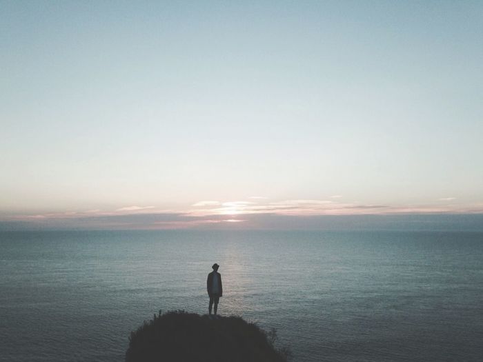 Silhouette man standing on beach against clear sky