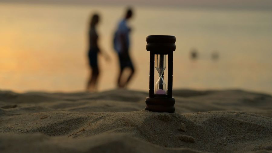 Hourglass on sand beach in sunset time means that  time is passing