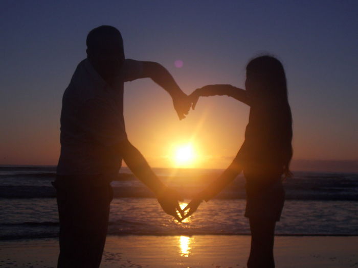 Father and daughter on beach at sunset