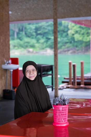 Portrait of woman wearing hijab sitting by table in restaurant