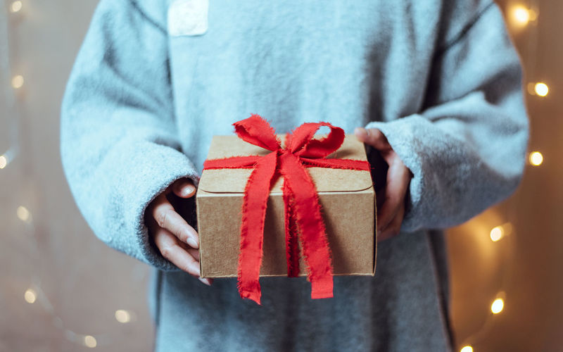 Midsection of woman holding gift box with red bow tie