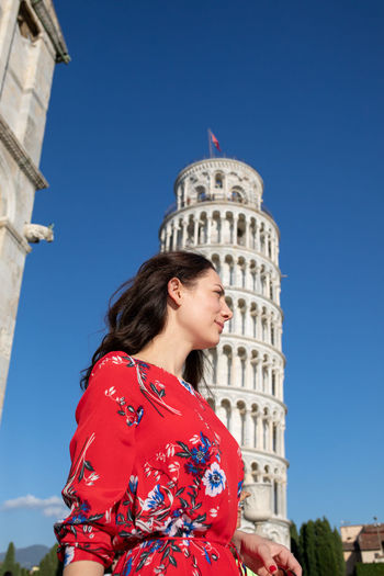 Smiling woman standing against leaning tower of pisa in italy