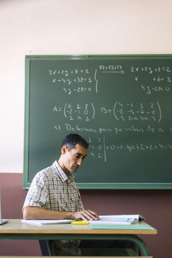 Math teacher sitting with book in classroom