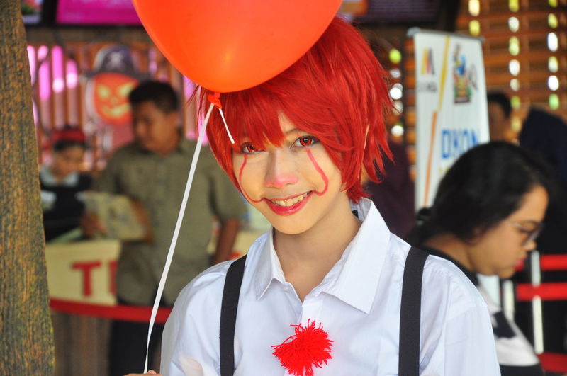 Portrait of smiling young woman with red balloon and painted face during halloween