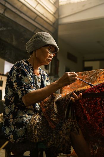 Side view of indonesian craftswoman making written batik