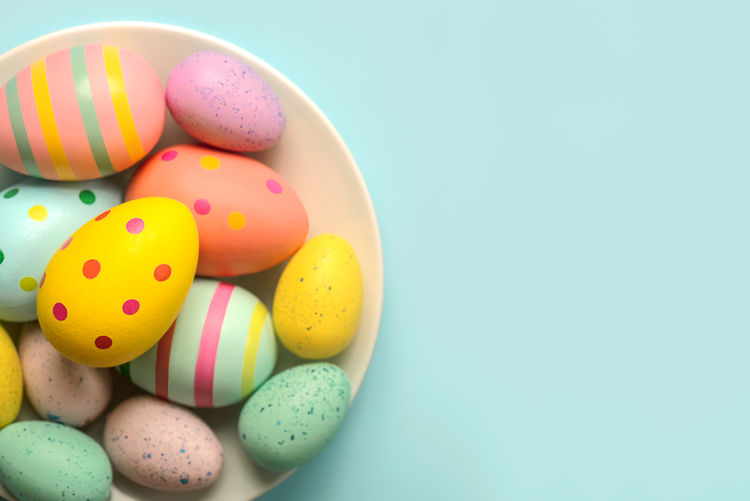 High angle view of easter eggs in bowl on blue background
