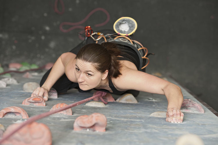 Young woman climbing at indoor climbing wall in england / uk