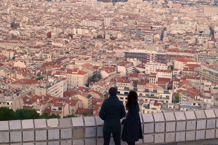 Rare view of couple standing by wall against cityscape