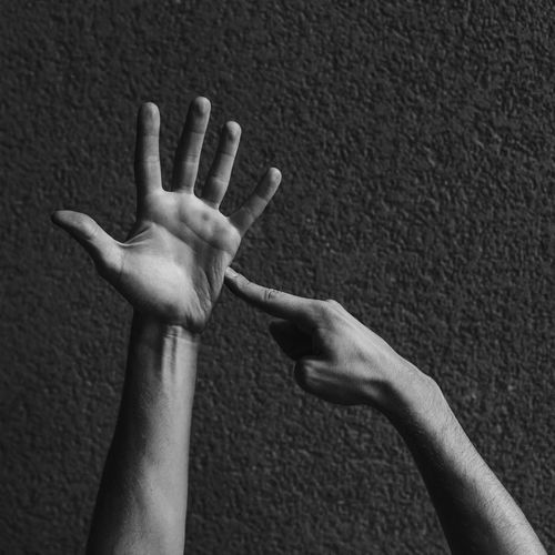 Cropped hands of man gesturing against wall