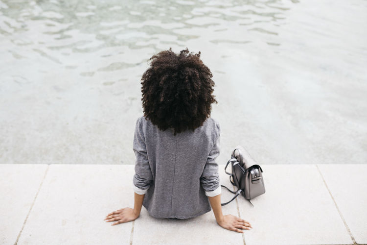 Back view of woman sitting at edge of a pool