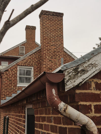Low angle view of man holding building roof against sky