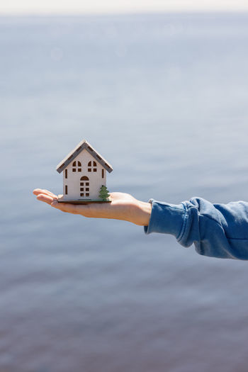 A house in miniature, a woman holds a mock-up of a house on her hand. design and sale of real estate
