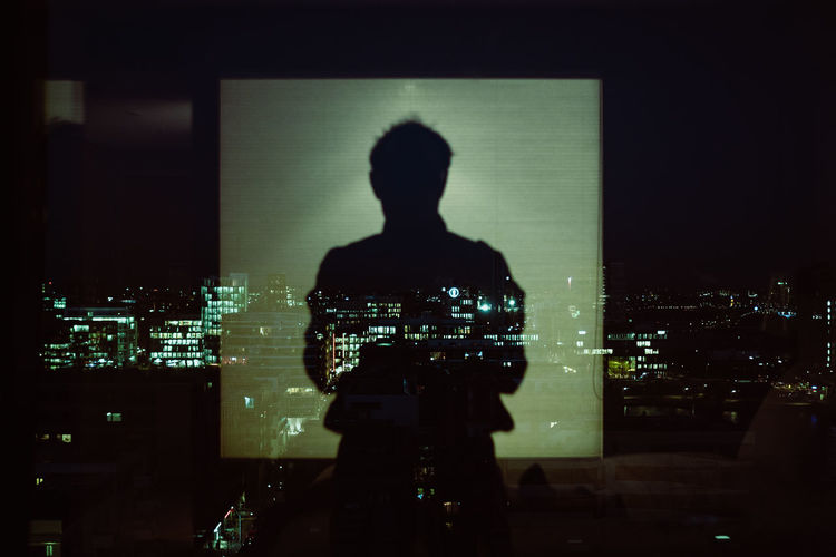 Reflection of silhouette man on glass window at night