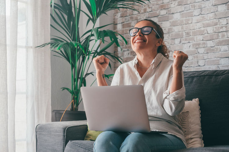 Young woman using laptop while sitting on sofa at home
