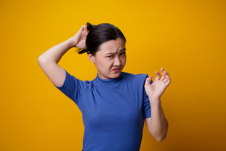 Mid adult woman standing against yellow background
