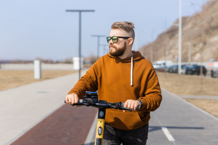 Man wearing sunglasses with scooter on road