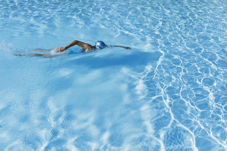 Woman swimming in clear blue swimming pool