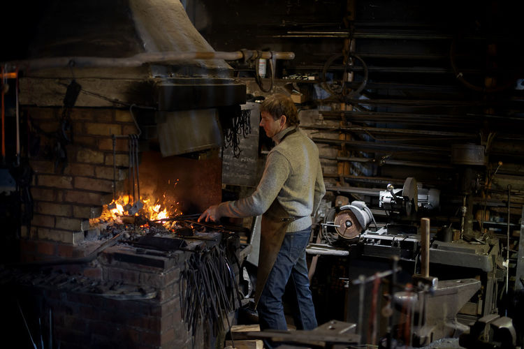 Latvian blacksmith working with open fire in furnace. the blacksmith forging hot iron in workshop