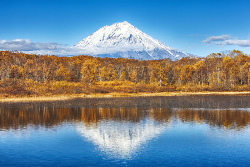 Panoramic autumn view of the koryaksky volcano reflected in the water of the lake. 