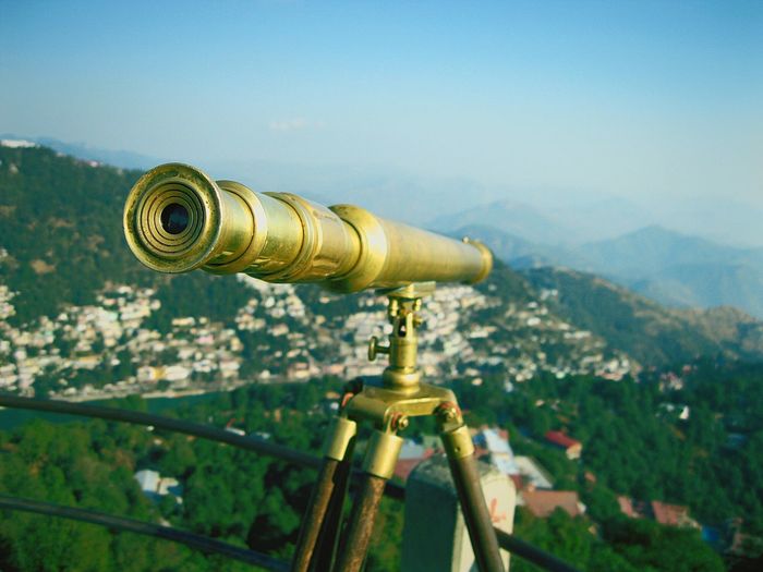 Close-up of old-fashioned metallic binocular over city