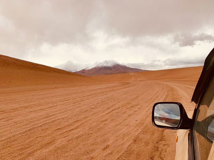 Off-road vehicle in desert against sky