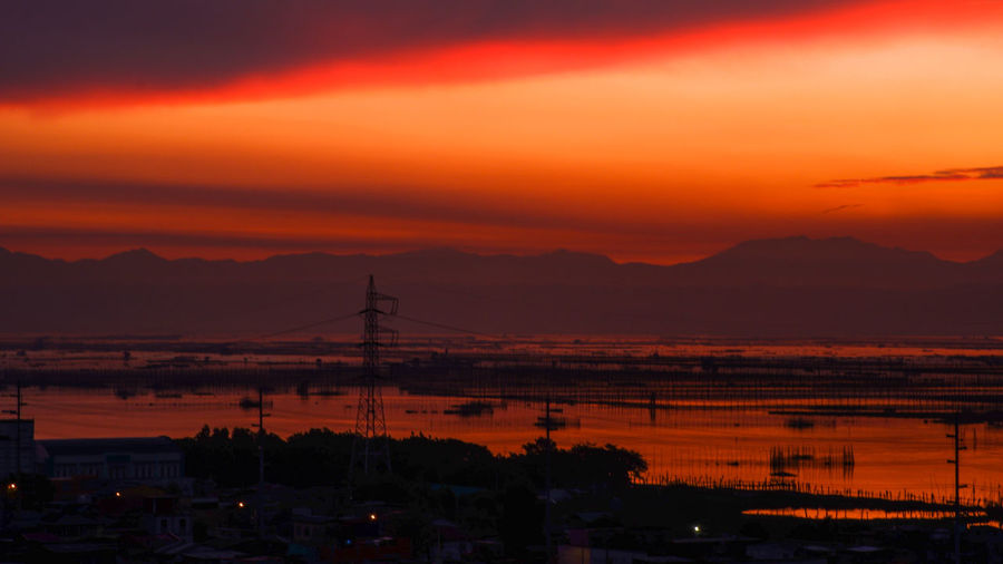 Silhouette cityscape against sky during sunrise
