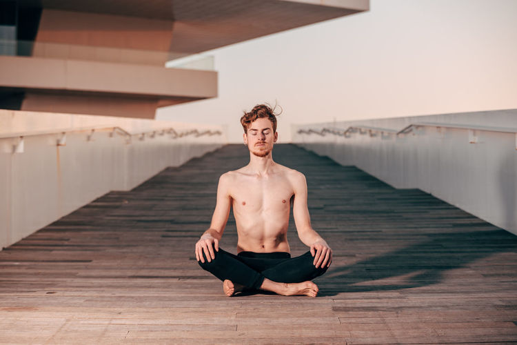 Full length of man mediating on bridge