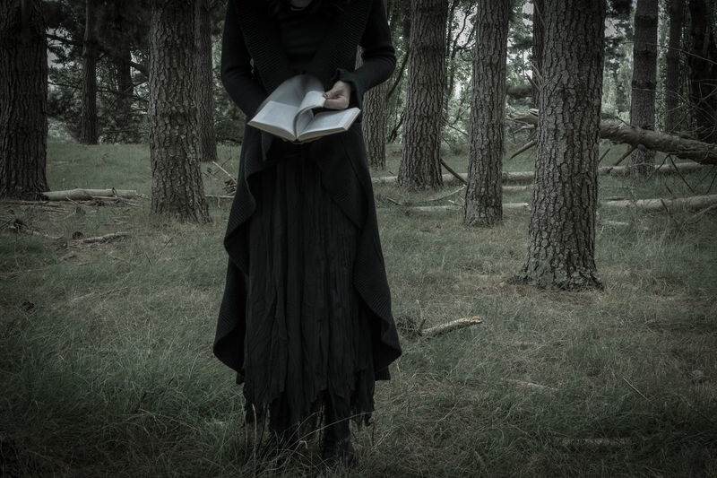 Bizarre woman reading a book in the forest
