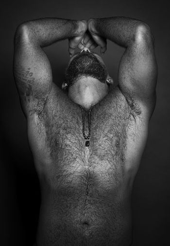 Midsection of shirtless man over black background