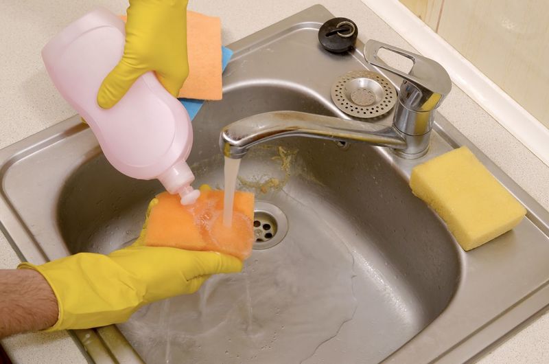 High angle view of man with sponge cleaning sink at home