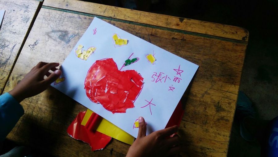 Close-up of child's hands with drawing of apple