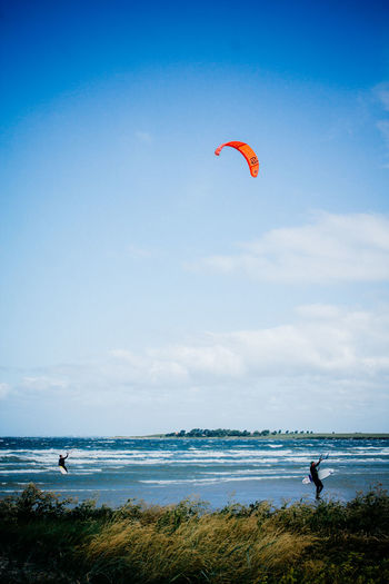 Men kiteboarding on sea against sky