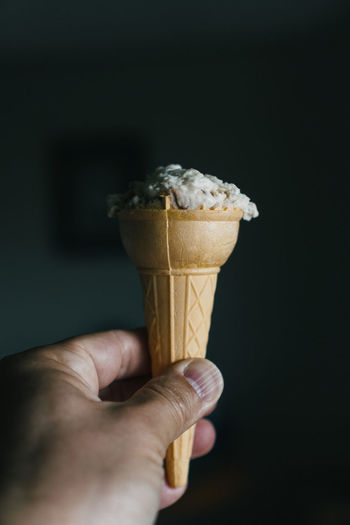 Adult male hand holding ice cream cone.