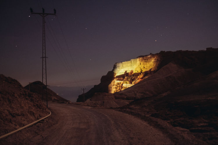 Road amidst rocks against sky at night