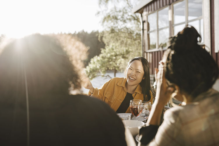 Happy woman talking with female friends in party on sunny day