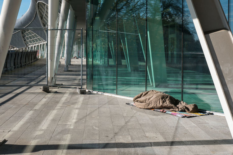 Homeless sleeping under warm blankets over a modern design bridge.