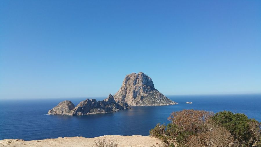 Scenic view of stack rock in sea against blue sky