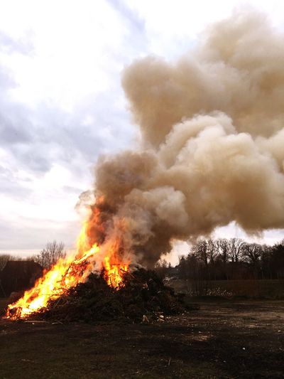 Bonfire on field against cloudy sky
