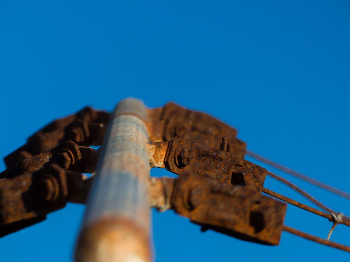 Low angle view of rusty metal against blue sky