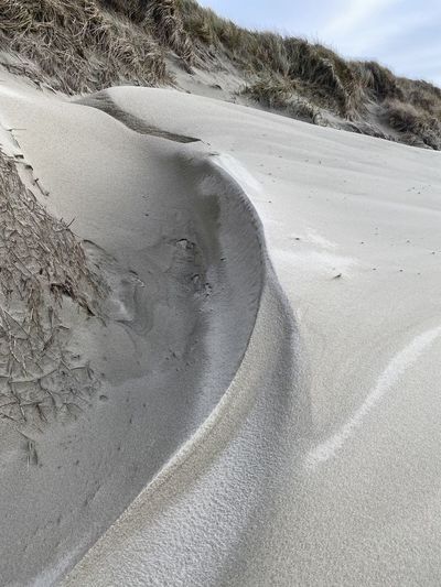 Scenic view of sand dunes at beach against sky