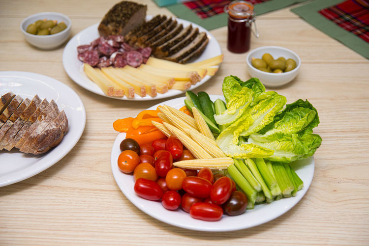Plate of cold snacks and appetizers like fresh baby plum tomatoes, mini corn, celery stalks, lettuce