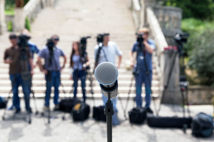 Close-up of microphone against people photographing outdoors