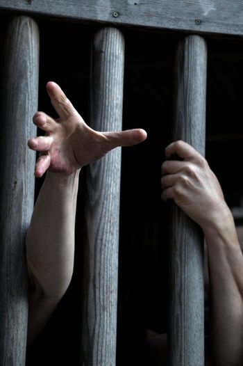 Prisoner behind wooden bars begging for help